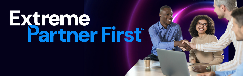 A diverse group of individuals shaking hands with a coffee cup and an open laptop on the table, depicting a strong partnership ecosystem stemming from Extreme Partner Portal. 